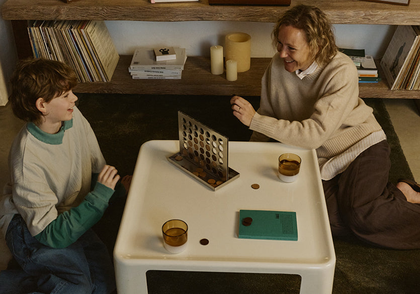 Two people sitting at a small table with a vintage computer model on it, in a cozy room.