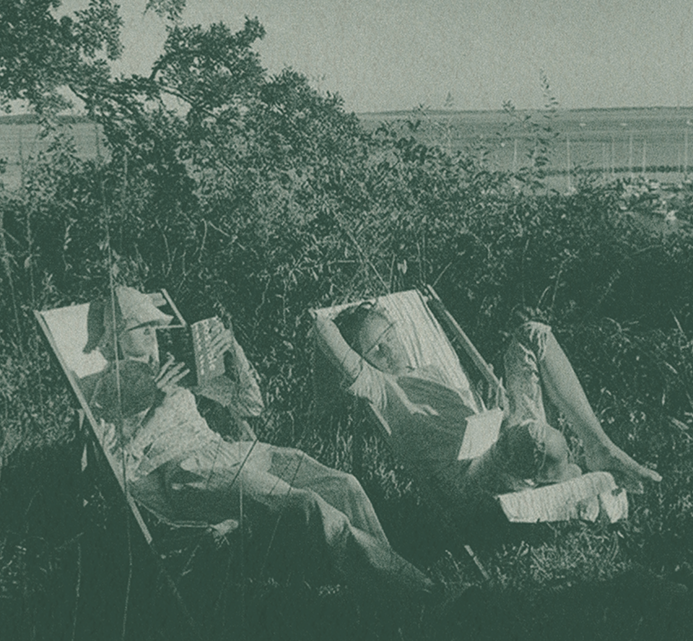 Two people relaxing on lounge chairs in a lush garden, reading and resting on a warm day