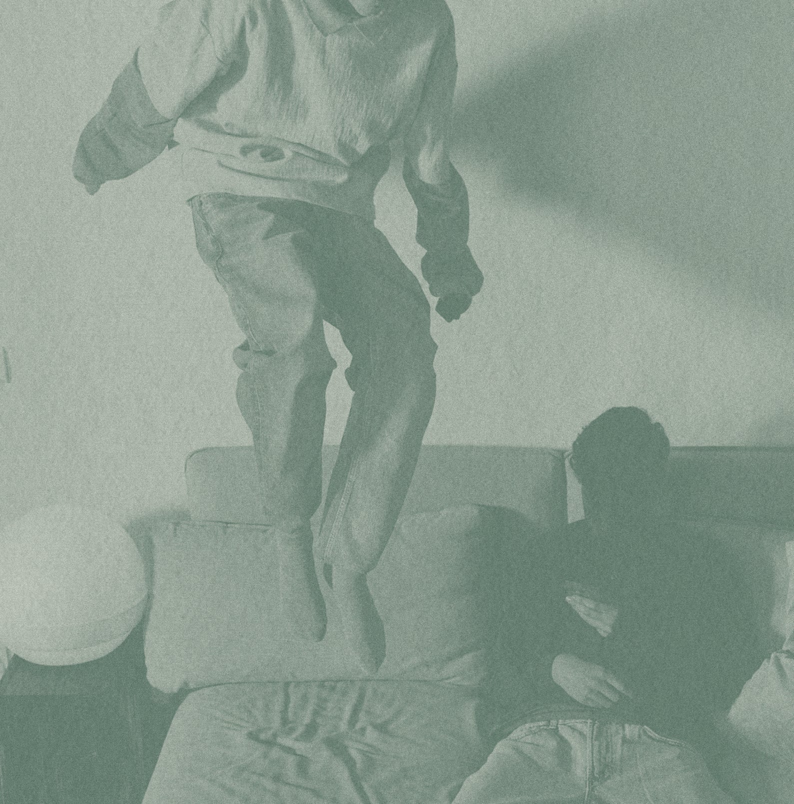 A young child lying upside down on a couch, smiling playfully at the camera with their hair hanging down