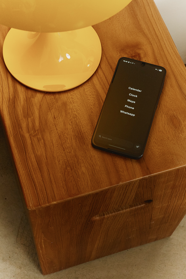 Smartphone on a wooden surface with a yellow lampshade in the background