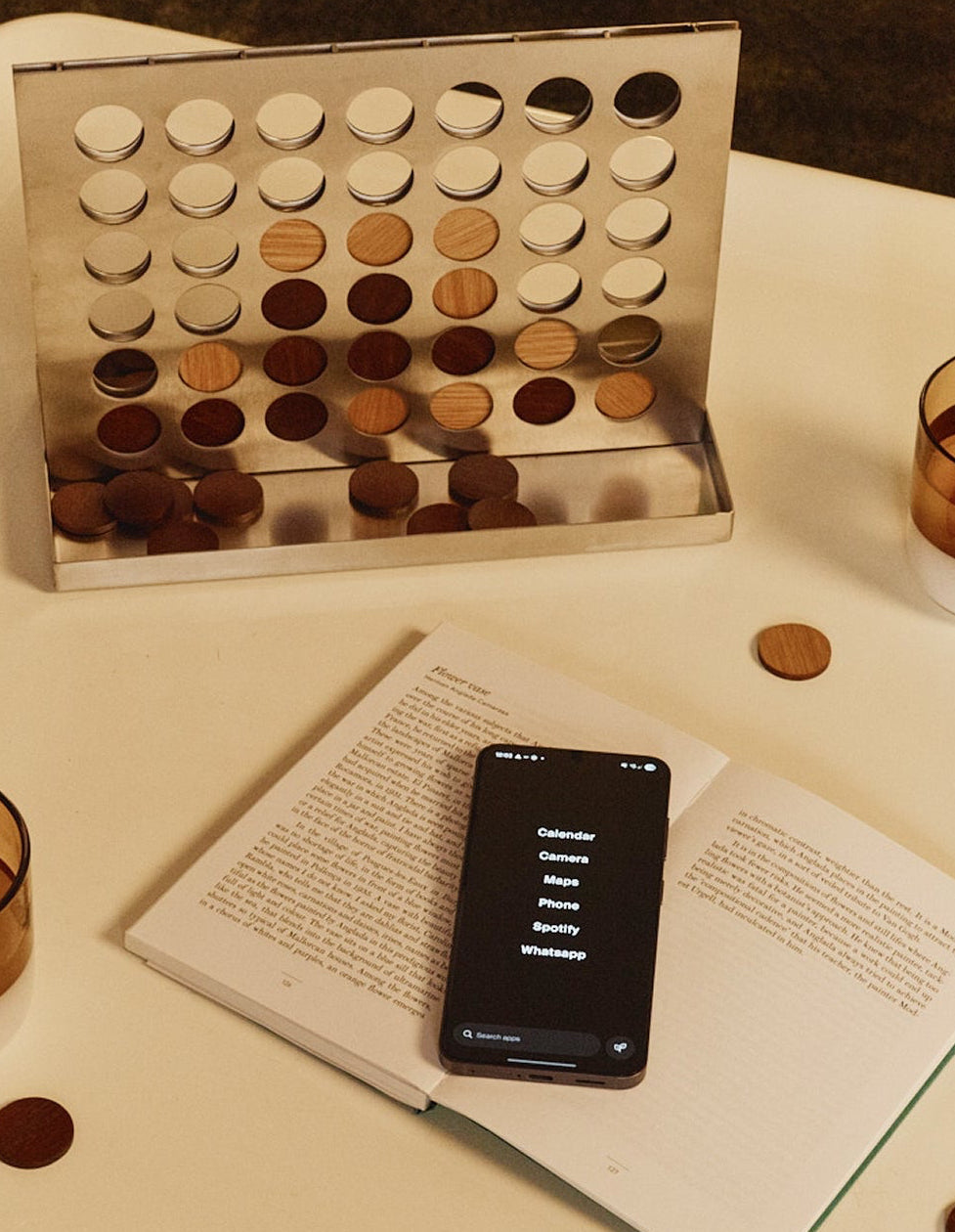 game, smartphone on an open book, and pieces on a table.