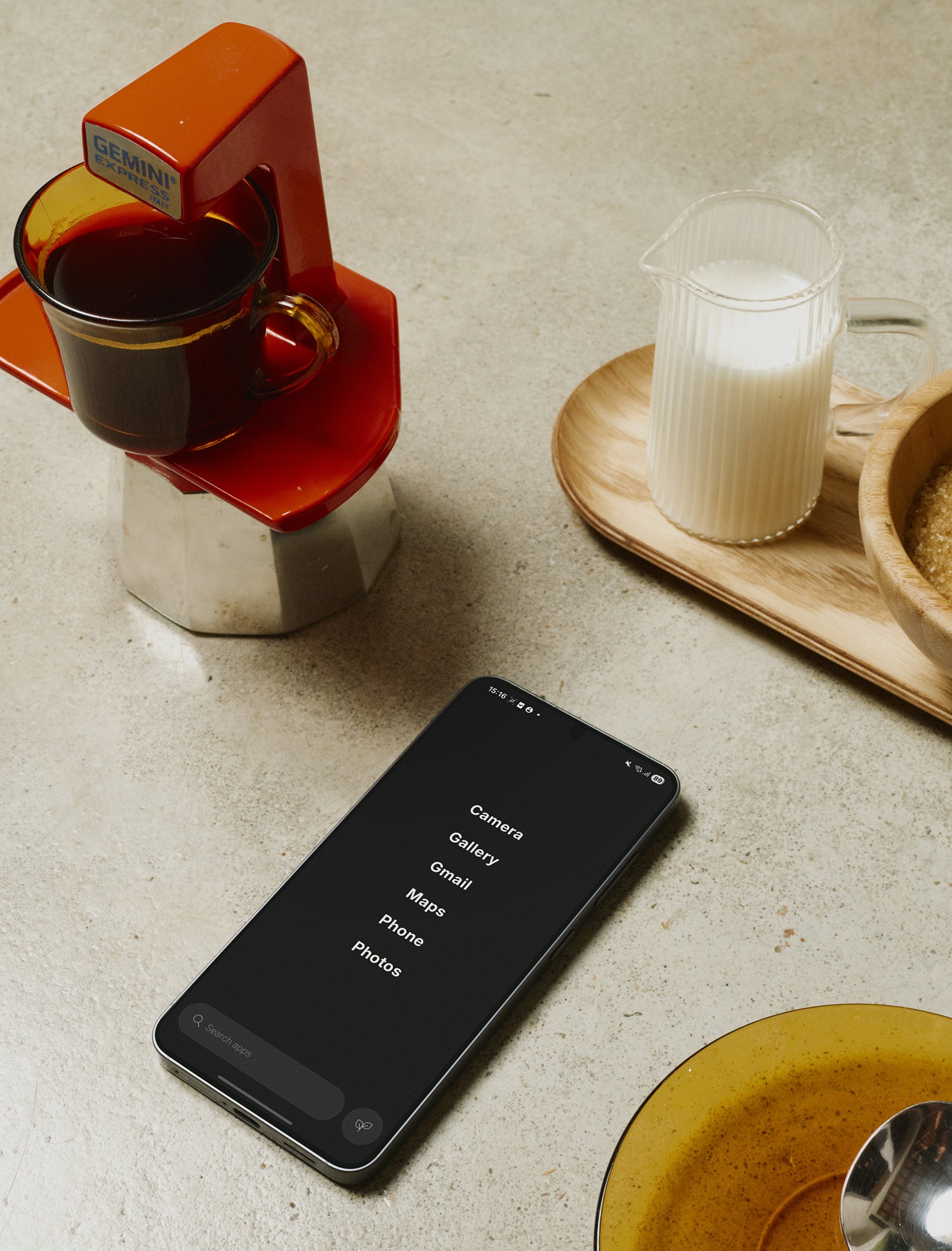 Smartphone on a kitchen counter with coffee-making device and milk in the background