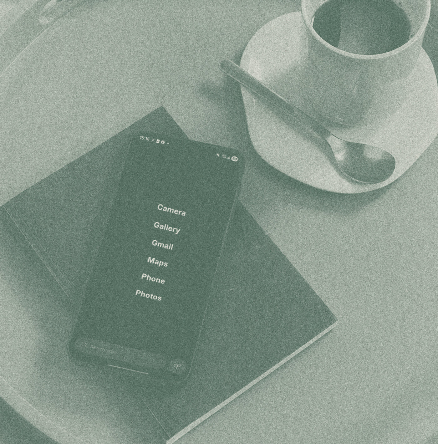 Phone with app icons on a table next to a cup and saucer