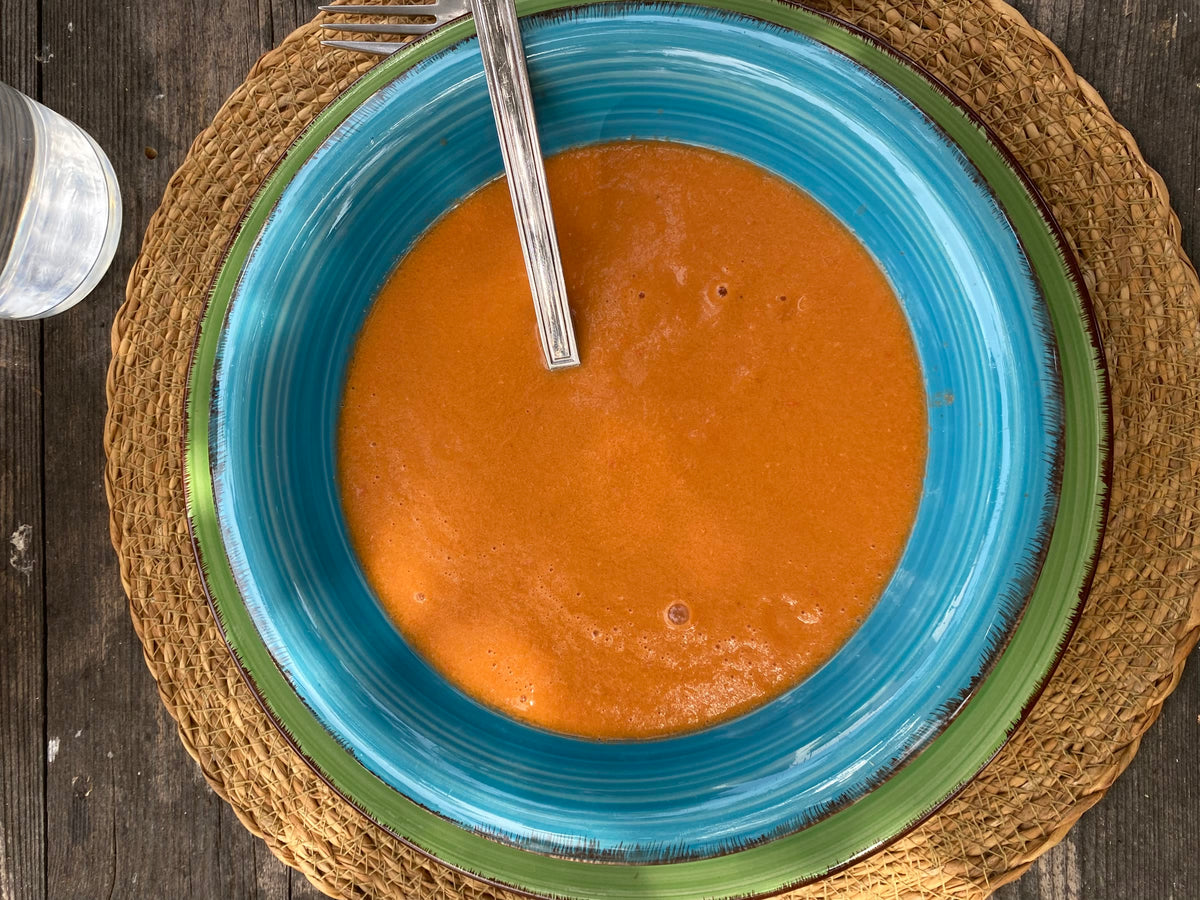 A bowl of gazpacho on a woven placemat
