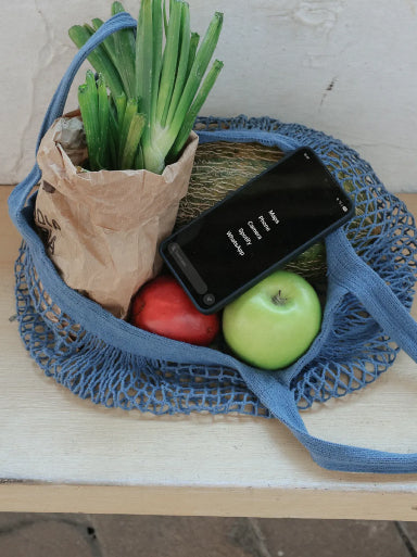 A Balance Phone tucked in a string grocery bag with vegetables