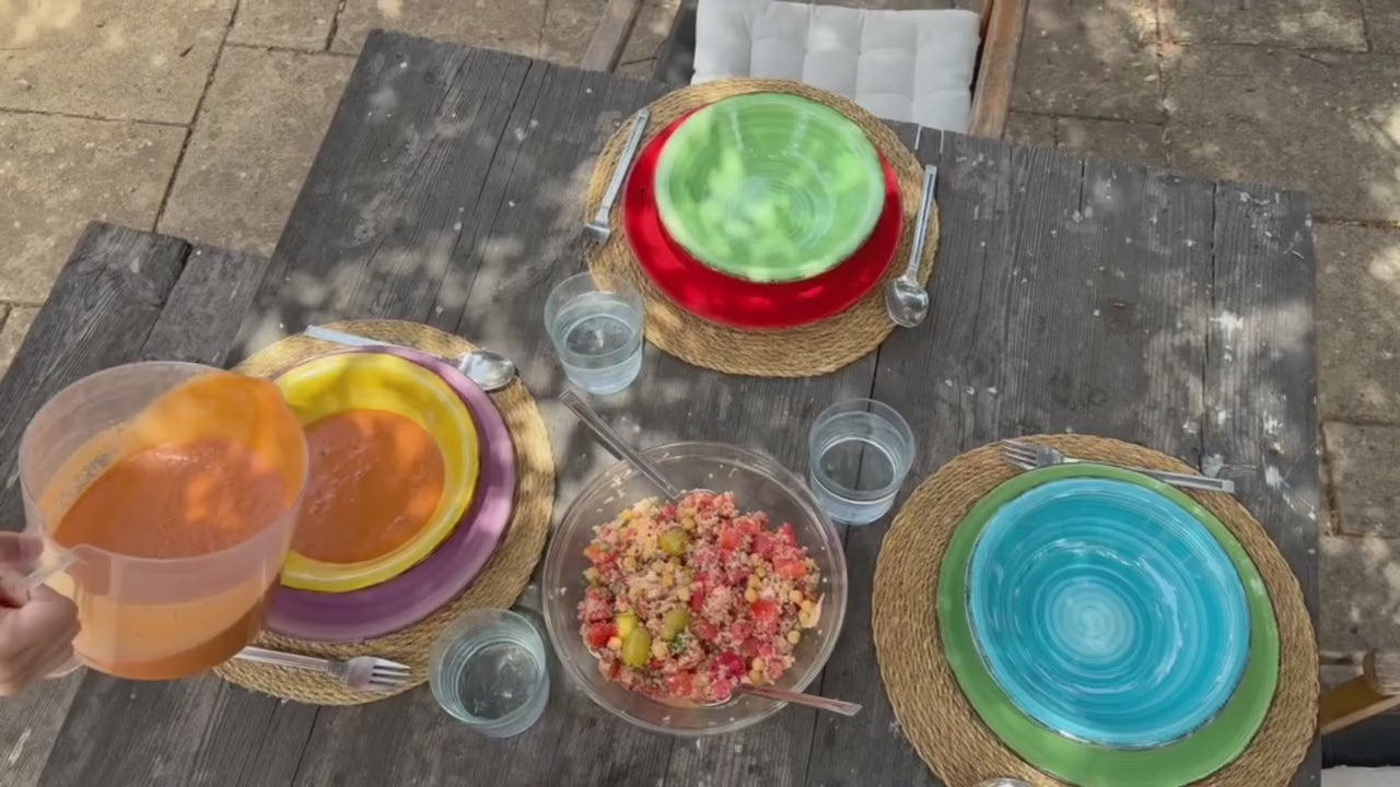A table set outdoors with gazpacho and salad